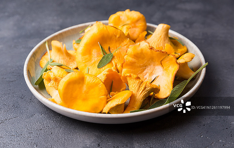 未经烹煮的野生鸡油菌及香料和香草，可用于烹饪，黑色背景上的野生蘑菇图片素材