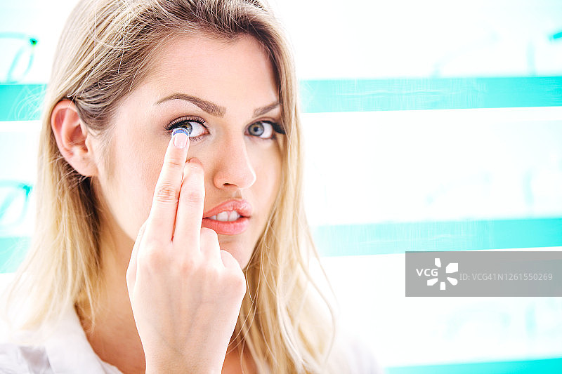 正在戴隐形眼镜的年轻金发女子图片素材