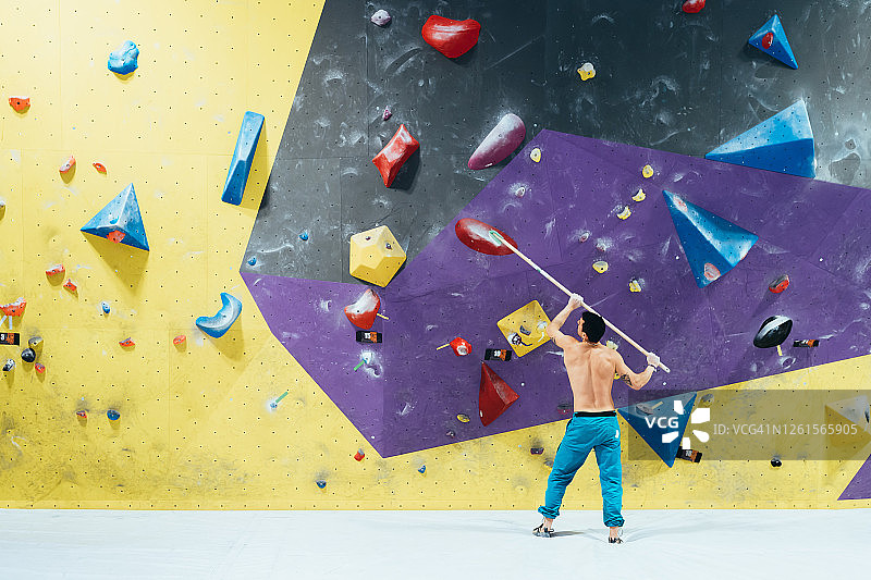 用扫帚刷攀岩墙的男人的后视图图片素材