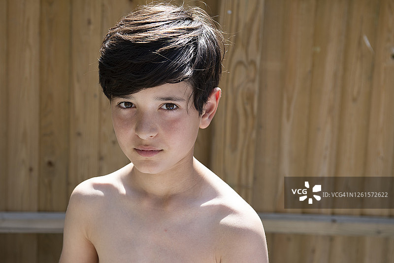 夏季花园里棕色头发男孩的肖像，看着镜头图片素材