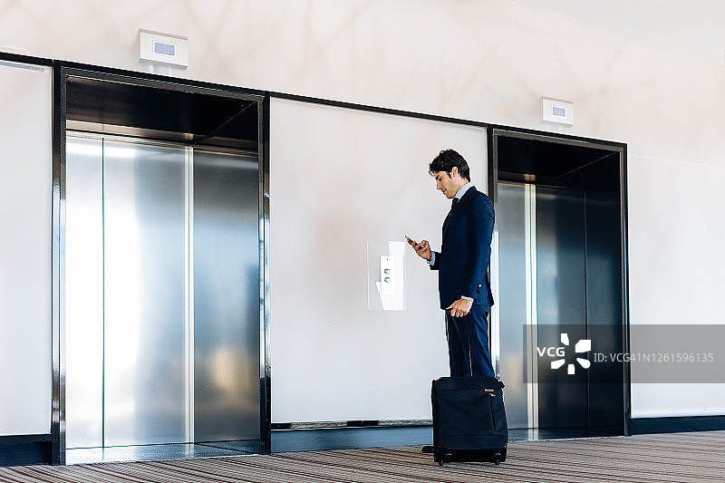 乘坐酒店电梯的商人，带轮式行李图片素材
