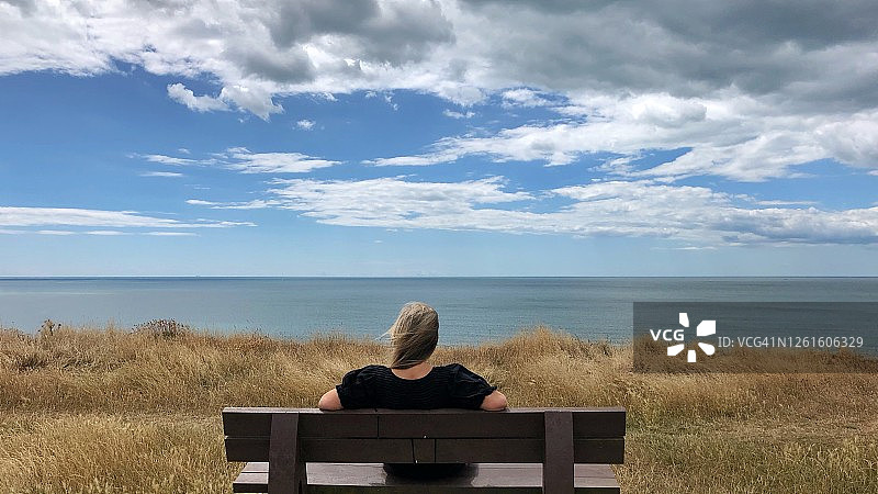 英国汉普郡海上巴顿，坐在长凳上看风景的女子背影图片素材