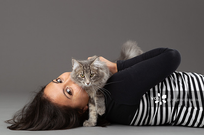 拥抱灰色猫的女人，灰色背景，影棚拍摄图片素材