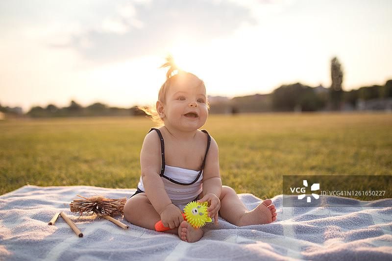 微笑的女婴在公园里玩玩具图片素材