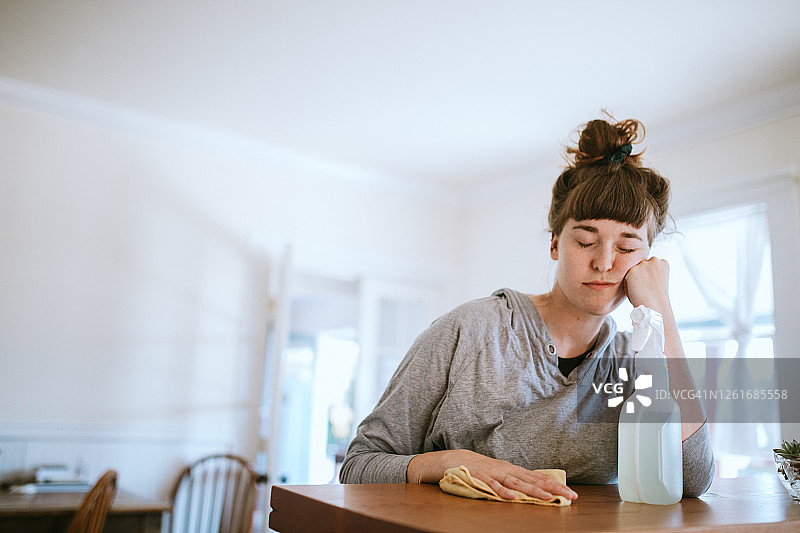 疲惫的女人用漂白剂清洁共用厨房图片素材