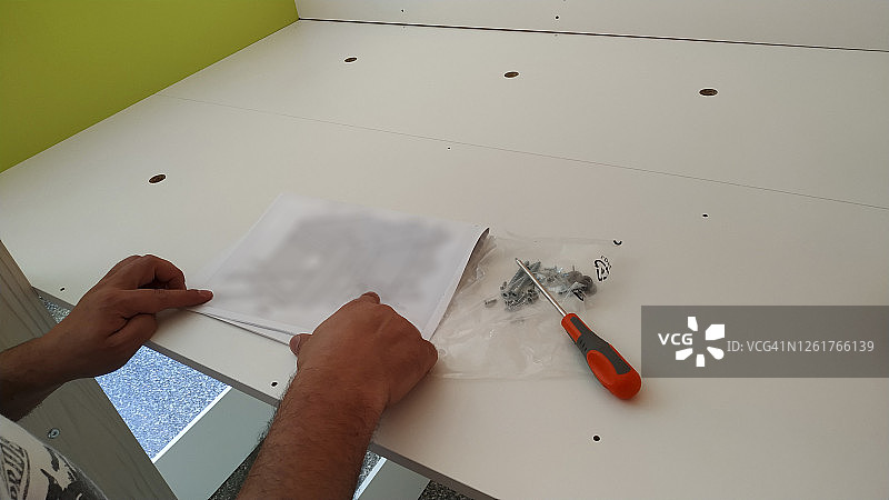 一名男子正在看家具的组装说明图片素材