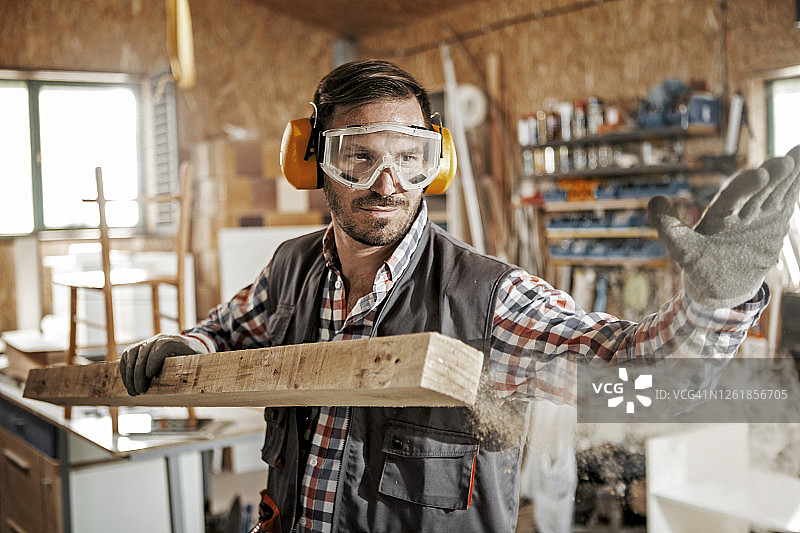 年轻木匠用手从木板上扫去木屑图片素材