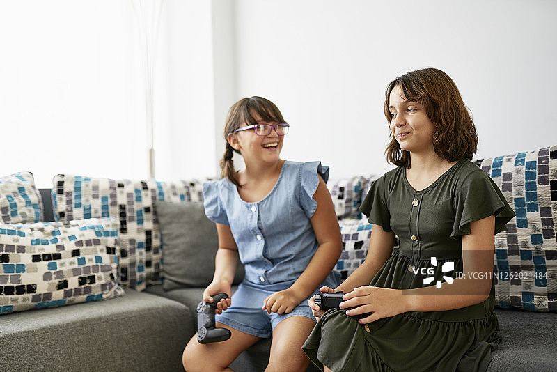 坐在沙发上玩电子游戏的两个女孩图片素材