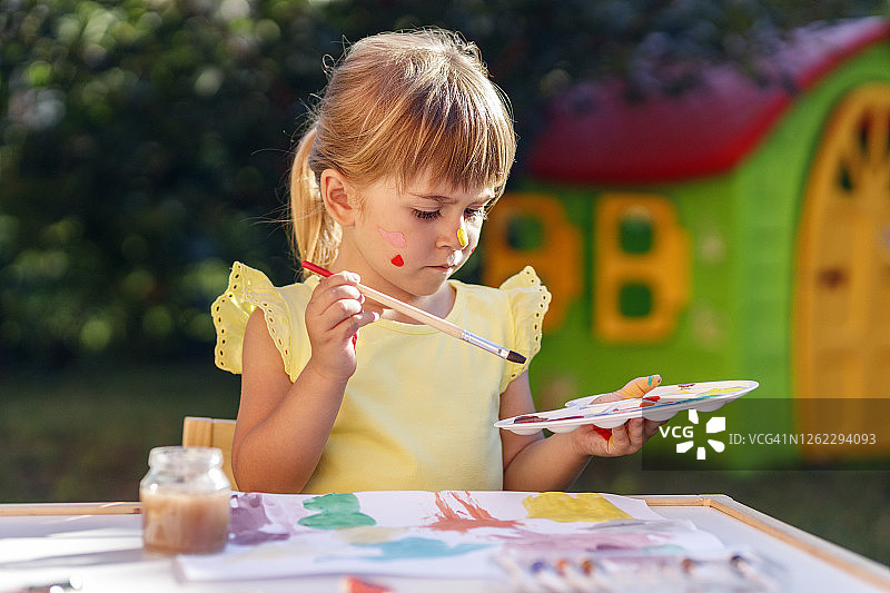 使用画笔和调色板时皱眉的严肃的年轻儿童图片素材