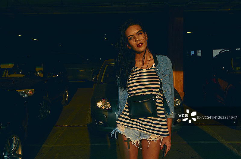 穿着热裤站在停车场上的棕色长发女人 портрет图片素材