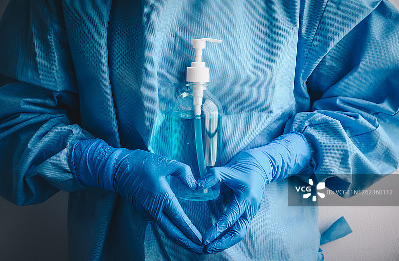 穿着医用刷手服的医护人员拿着洗手液，比心图片素材