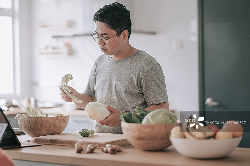 中国中年男子在厨房准备沙拉图片素材