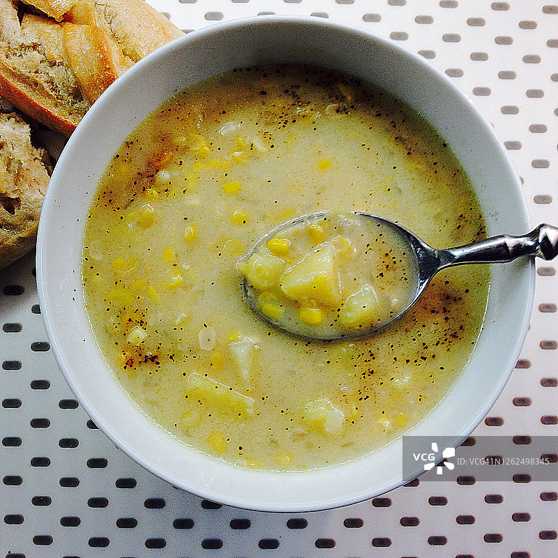玉米浓汤特写：育空金土豆、黑胡椒碎、面包和勺子图片素材