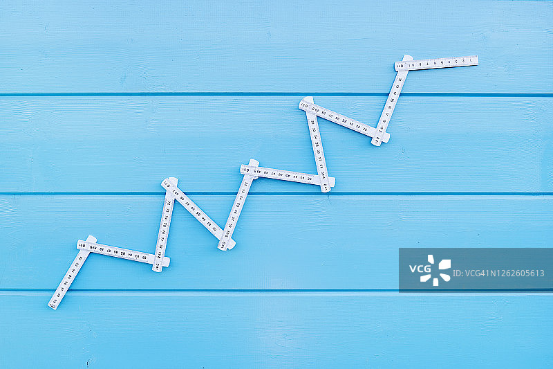 蓝色木纹背景上的股票曲线折叠尺图片素材