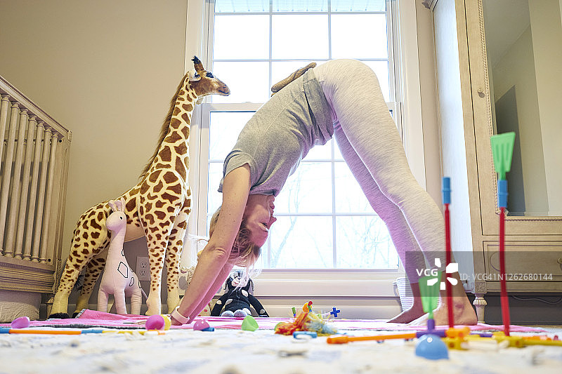 年轻妈妈在女儿的房间里做下犬式瑜伽图片素材
