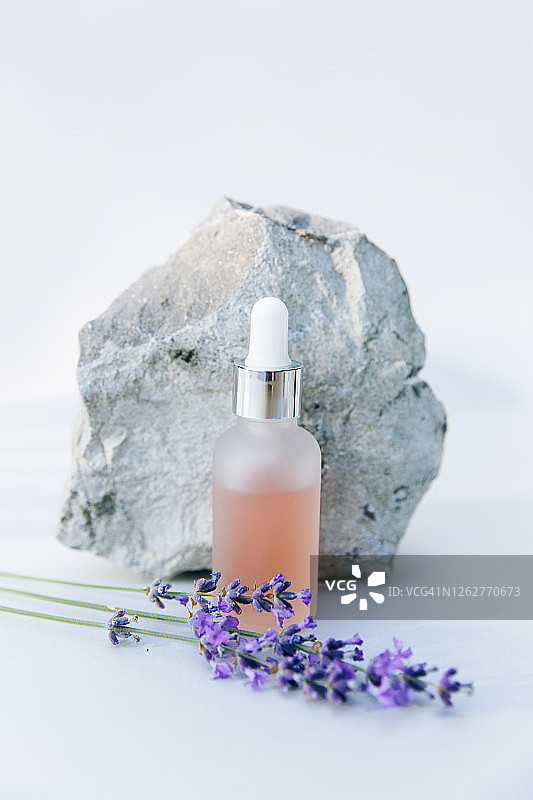 石台上瓶装大理石玻尿酸和胶原蛋白，含薰衣草和鲜花（正面图）图片素材