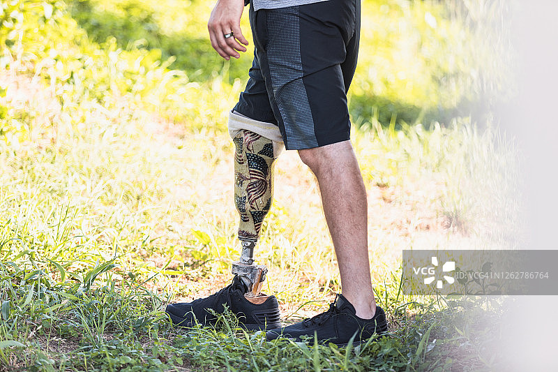 男子站在草地上，展示假肢图片素材