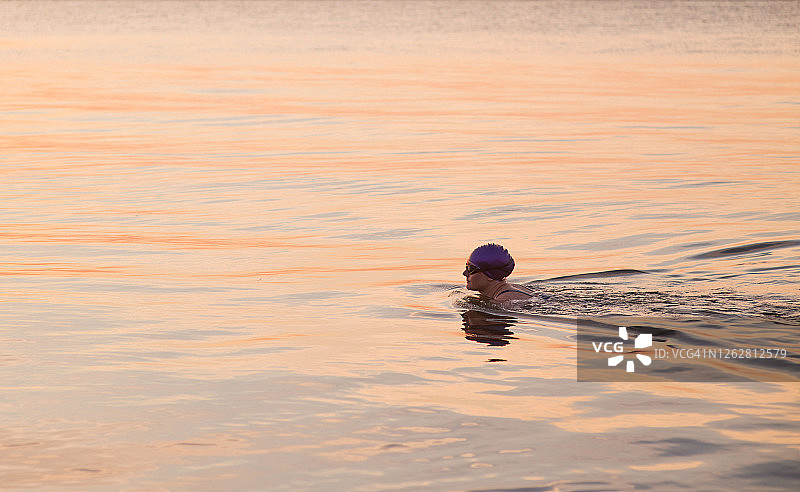 日落时在海中的女游泳运动员图片素材