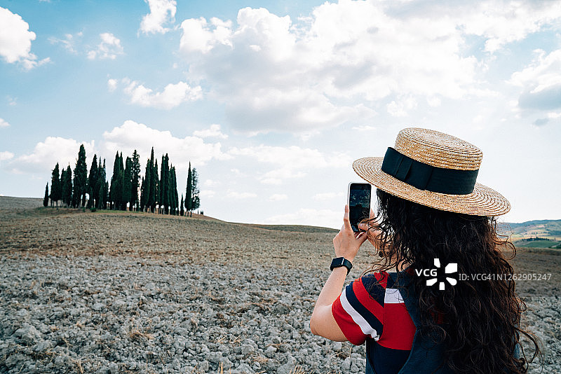 年轻女人在托斯卡纳瓦尔道尔恰拍摄柏树群图片素材