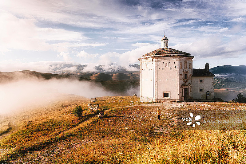 大萨索国家公园卡拉肖罗卡附近的圣玛丽亚德拉彼埃塔教堂。前景是穿着黄色雨衣的女人。图片素材