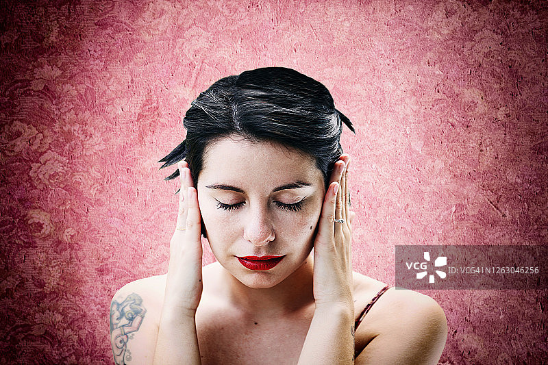 在粉色墙前患偏头痛的女人图片素材