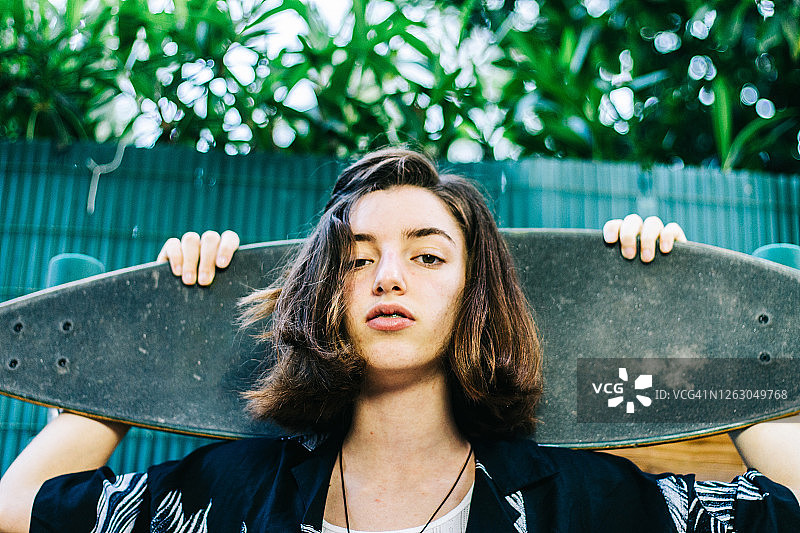 背着滑板、穿着夏威夷衬衫的少女图片素材