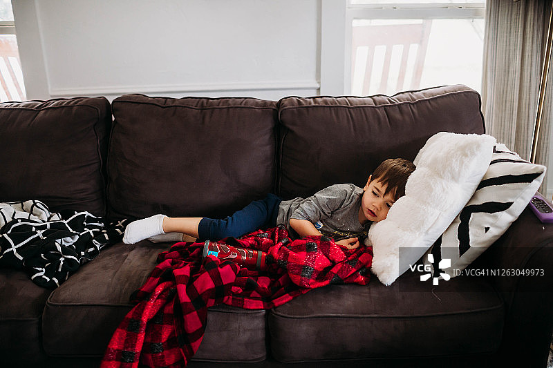 生病的儿童躺在客厅的沙发上图片素材