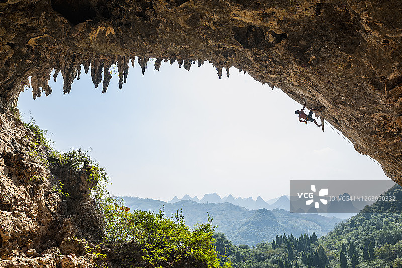 在阳朔月亮山旁奥丁洼地攀爬拱门的男人图片素材