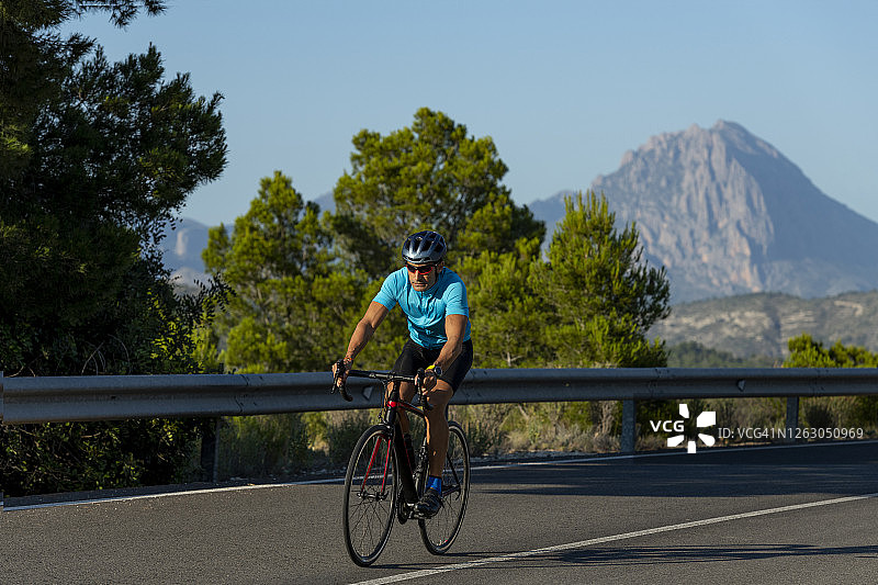 男子在白色海岸山路上骑自行车图片素材