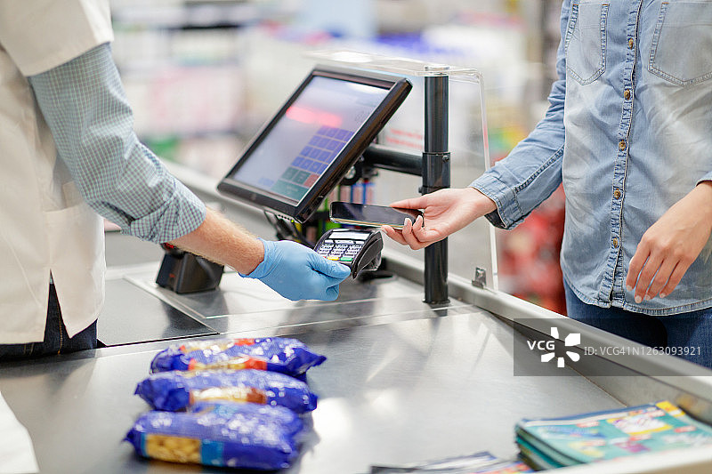 在超市收银台用智能手机非接触式支付图片素材