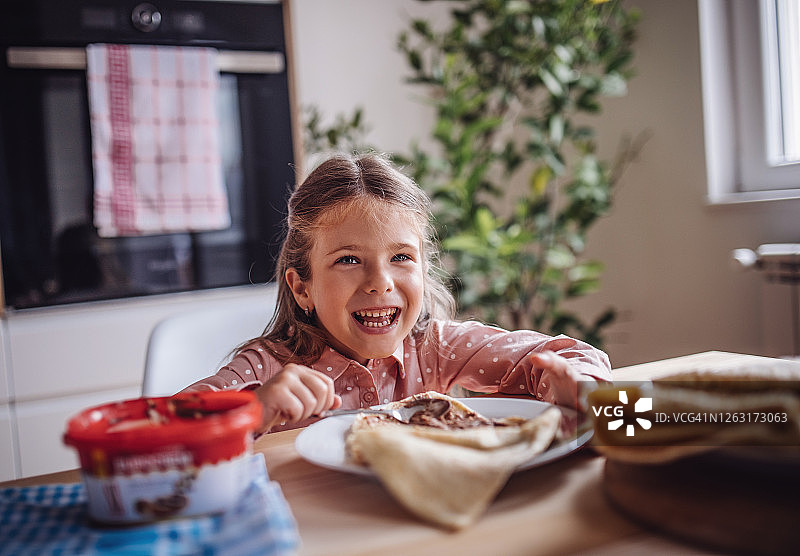可爱幼儿女孩吃自制巧克力奶油薄饼图片素材