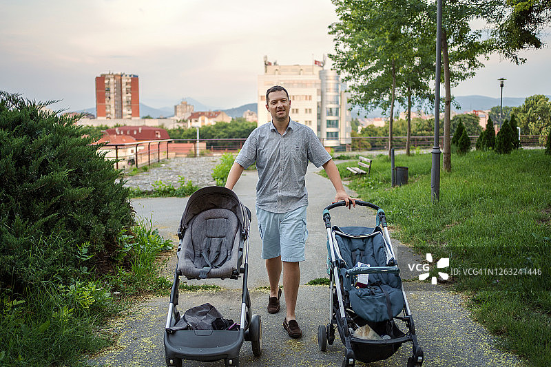 父亲在公园里推着两辆婴儿车图片素材