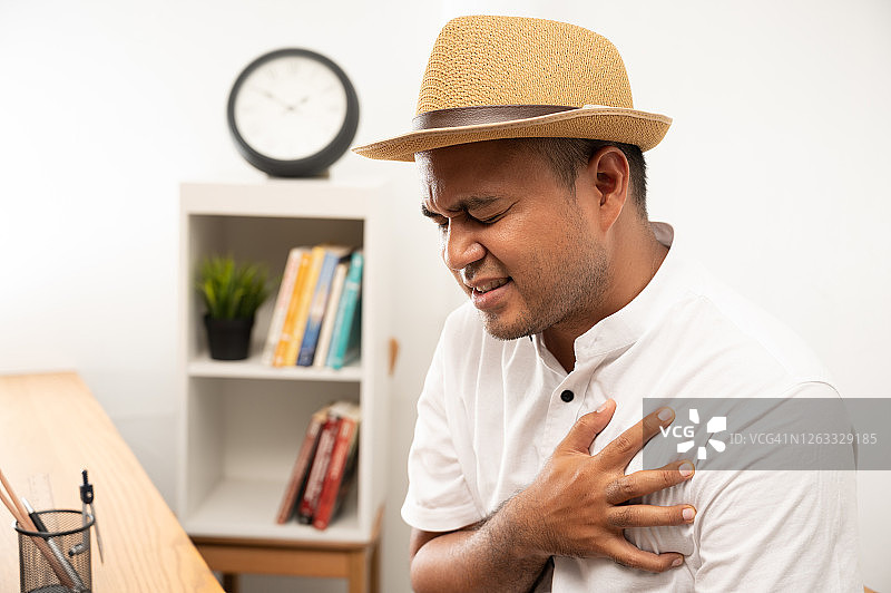 男人患有心脏病，手捂胸口，突发心脏病，症状是疼痛图片素材