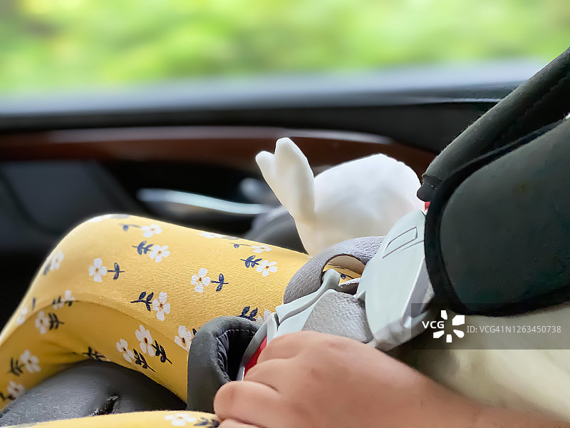 在汽车座椅上睡觉时抱着玩具兔子的混血女童图片素材