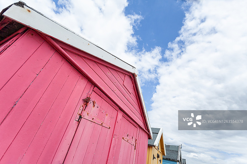 阴天时英国海边传统的彩色海滩小屋图片素材
