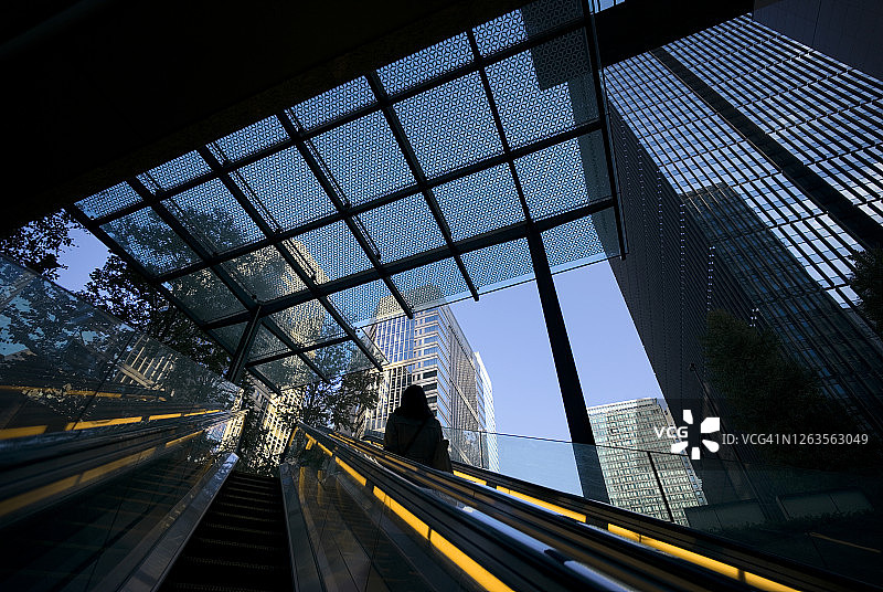 黎明时分到达现代商业区的自动扶梯上的女人图片素材
