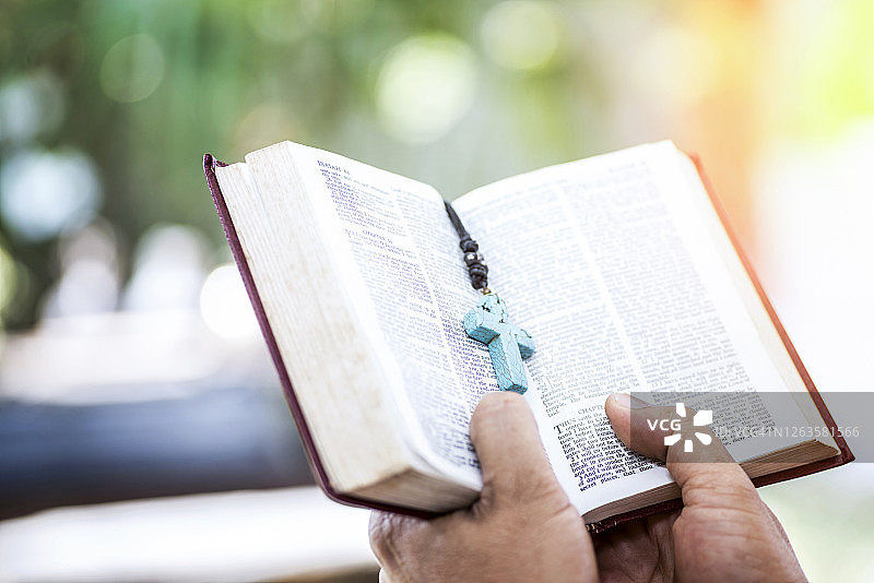 年轻男子双手捧读圣经，基督教信仰概念图片素材