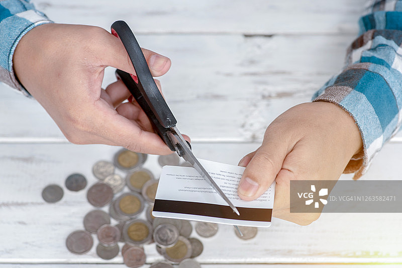 手用剪刀在桌子上剪信用卡图片素材