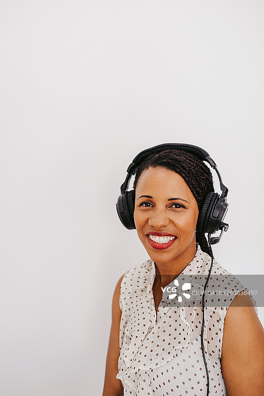 戴着耳机在白色背景下的美丽的年轻非裔美国妇女图片素材