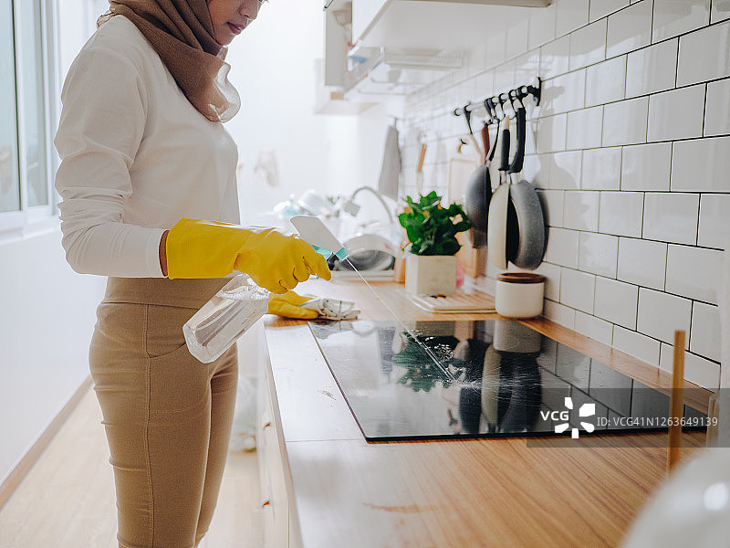 年轻的穆斯林妇女在家清洁厨房台面图片素材