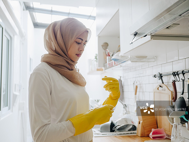 年轻的穆斯林妇女在家清洁厨房台面图片素材