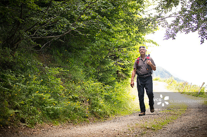 夏季在山路上徒步的年长男士图片素材