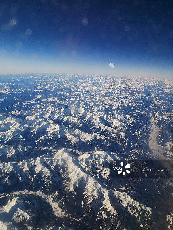 飞机窗口俯瞰地球：厚厚的云层，低光和蓝色背景图片素材