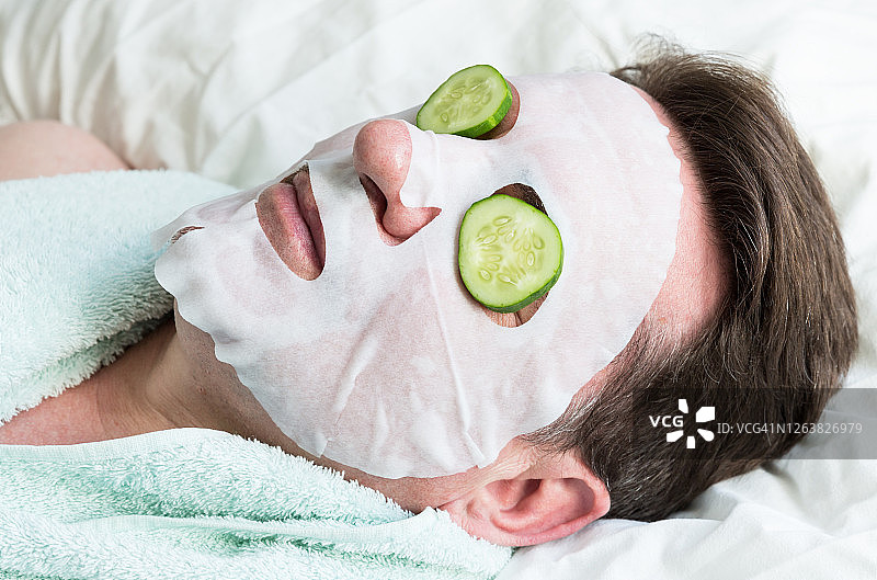 敷着面膜的男人面部。老年男子在家自制面膜，在家放松和身体护理。图片素材