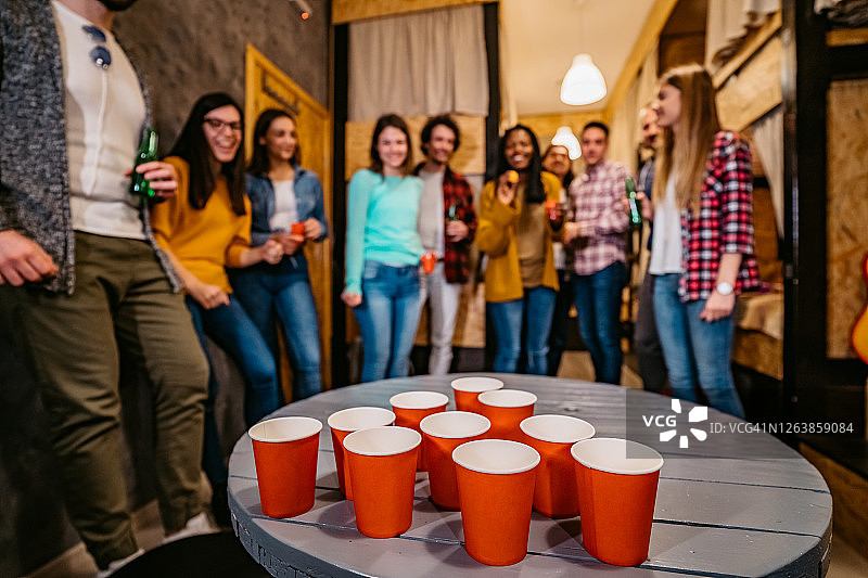 在青年旅社玩啤酒乒乓球的年轻人图片素材