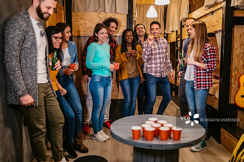 在青年旅社玩啤酒乒乓球的年轻人图片素材