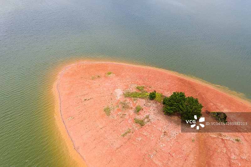 空旷的红土地上的一棵树，周围是海水图片素材