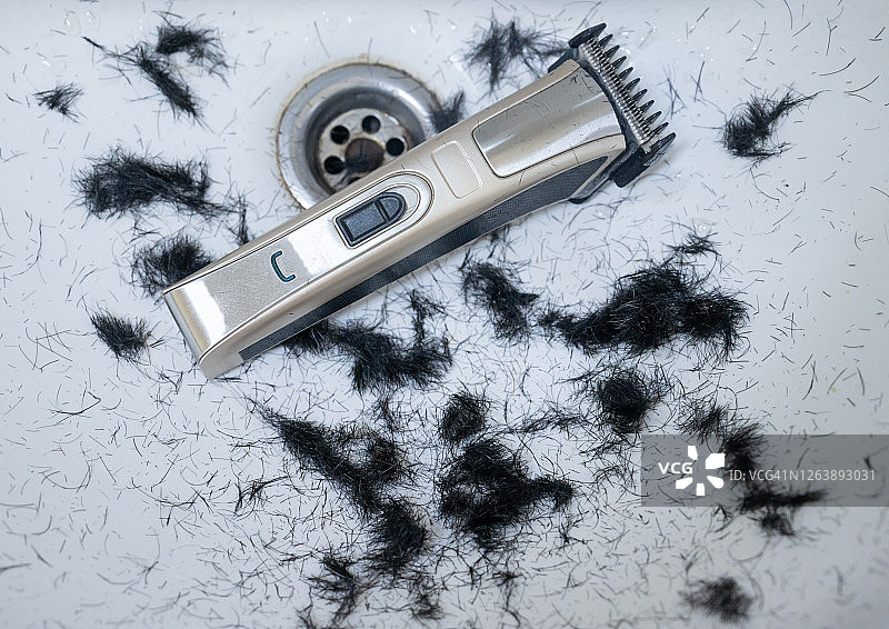 理发推子和掉落在浴室洗碗池里剪下的男士头发图片素材