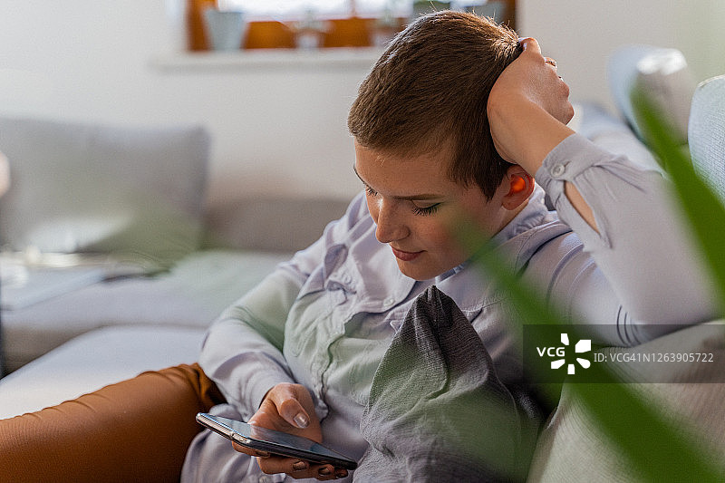 坐在沙发上玩手机的慵懒女人图片素材