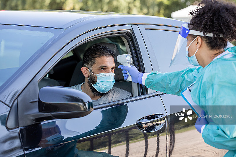护士在新冠病毒检测点为男人测量体温图片素材